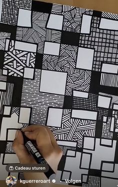 someone is drawing on a piece of paper with black and white squares in the background