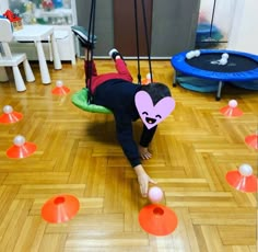 a child on a swing in the middle of an indoor play area with plastic balls