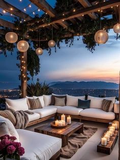 an outdoor seating area with candles on the table and lights hanging from the ceiling above it