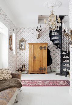 a room with a bed, dresser and chandelier hanging from the ceiling in front of a spiral staircase