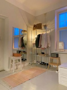 a white room with clothes on racks and a rug