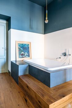 a bathroom with blue walls and wooden steps leading up to the bathtub in the corner