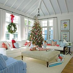 a living room filled with white furniture and a christmas tree in the middle of it