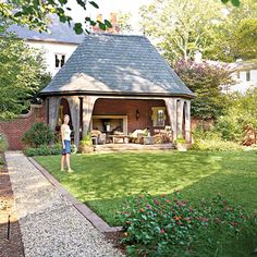 a woman is standing in the yard near a gazebo