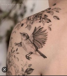 a bird on the back of a woman's shoulder with leaves and flowers around it