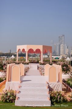 an outdoor ceremony setup with white and pink flowers on the ground, in front of a city skyline