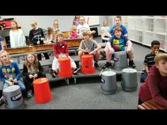 a group of children sitting around orange buckets