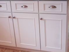 a kitchen with white cabinets and brown flooring