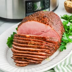 sliced ham on a plate with parsley next to an instant pot roaster oven