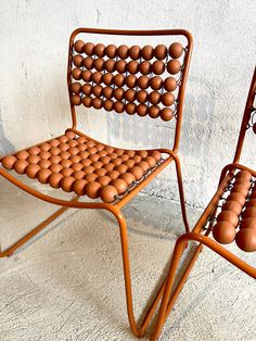 two chairs made out of egg shells sit side by side in front of a wall