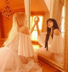 a woman in a white dress is looking at herself in the mirror with her reflection