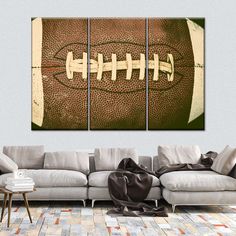 a living room scene with a couch and two paintings on the wall, one has a football