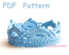 a crocheted blue crown sits on a white surface with the words pattern below it