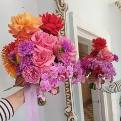 a woman holding a bouquet of flowers in front of a mirror