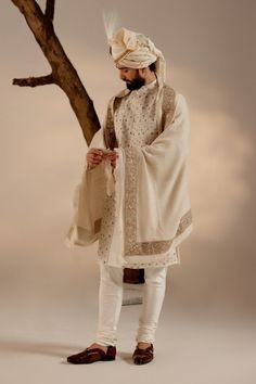 Turtle Dove Sherwani Set | Jatin Malik Introducing our renowned Kashmiri Jamawar embroidered sherwani, crafted in a captivating dirty ivory hue and adorned with intricate floral design details. This masterpiece is further elevated with exquisite dabka and zari work, adding a touch of opulence and refinement. Paired with a matching Ladakhi Pashmina shawl and safa, this ensemble exudes timeless elegance and sophistication, perfect for special occasions and celebrations. With its impeccable craftsmanship and attention to detail, this sherwani set is sure to make a memorable statement. Included in purchase: Sherwani, Kurta, Churidar, Pashmina Shawl, Safa Product Specification Color: White Fabric: Linen silk Occasion: Engagement, Wedding, Bridal, Reception Style: Sherwani, Kurta, Churidar, Pash Off White Bandhgala With Naqshi For Festive Occasions, Off White Naqshi Bandhgala For Festive Occasions, Traditional Raw Silk Bandhgala With Chikankari Embroidery, Eid Bandhgala With Chikankari Embroidery In Jamawar, Cream Sherwani With Chikankari Embroidery And Long Sleeves, Cream Long Sleeve Sherwani With Chikankari Embroidery, Designer Traditional Drape Off White Kurta, Festive Off White Bandhgala With Naqshi, Off White Bandhgala With Naqshi For Diwali