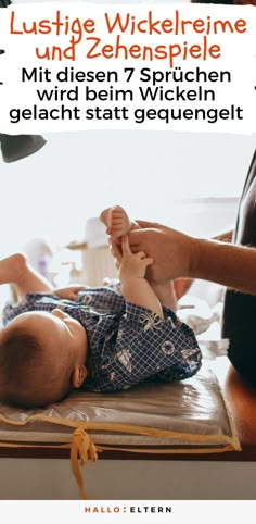 a baby laying on top of a wooden table next to a person holding a toy