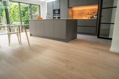 an open kitchen and dining area with wood flooring, glass doors to the outside