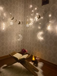 an open book sitting on top of a wooden table in front of a wall with lights