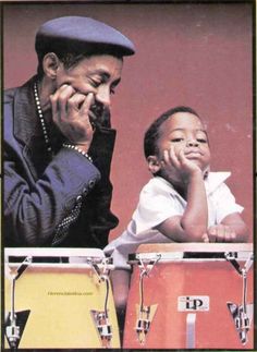 an older man and young child playing with musical instruments in front of a red background