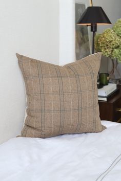 a bed with a pillow on top of it next to a night stand and lamp