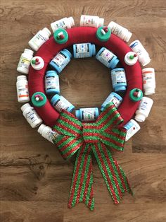 a christmas wreath made out of baby bottles on a wooden floor with red and green ribbon