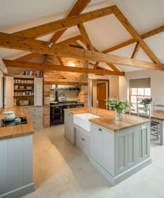 a large kitchen with an island in the middle and wooden beams on the ceiling above it