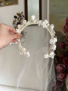 the bride is holding her wedding tiara with pearls and flowers on it's head