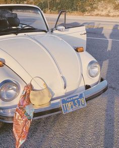 an old white vw bug parked on the side of the road