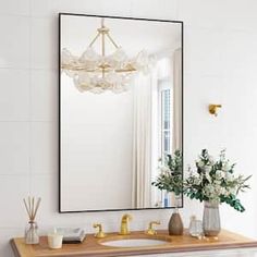 a bathroom sink with a mirror above it and flowers in vases on the counter