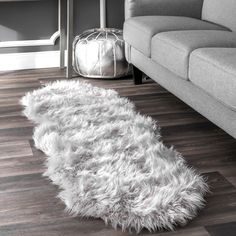 a living room with a gray couch and white sheepskin rug on the wooden floor