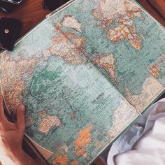 a person sitting at a table with a map in front of them and cell phones on the floor