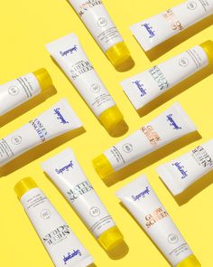 eight tubes of sunscreens sitting on a yellow background with one tube in the middle