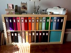 a book shelf filled with lots of books on top of a hard wood floor next to a wall