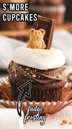 a chocolate cupcake with a teddy bear on top and the words, s'more cupcakes fudge frosting