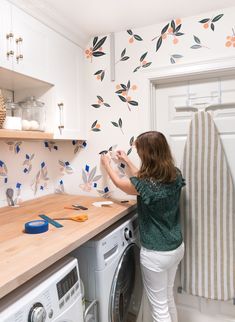 a woman standing next to a washer in a kitchen