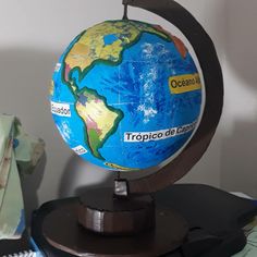 a blue and yellow globe sitting on top of a wooden stand next to a pile of books