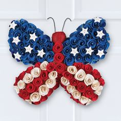 a butterfly made out of red, white and blue paper flowers is hanging on a door