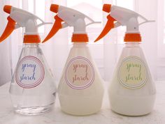 three spray bottles with labels on them sitting on a counter