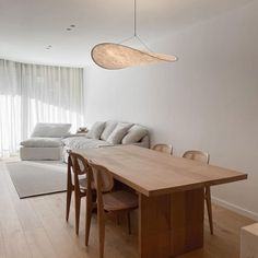 a living room and dining area with white walls, wood flooring and wooden furniture