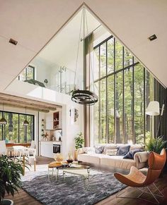 a living room filled with lots of furniture and large windows in the wall above it