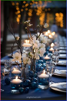 the table is set with candles, flowers and glass vases for centerpieces