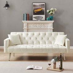 a white couch sitting on top of a hard wood floor next to a fire place