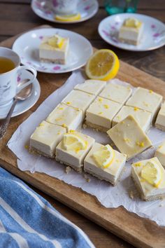 several pieces of cake on a cutting board with tea and lemons in the background