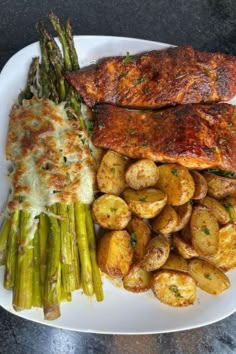 a white plate topped with meat, potatoes and asparagus