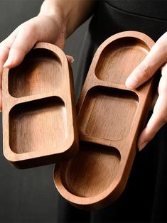 a person holding two wooden trays in their hands, one is empty and the other has three compartments