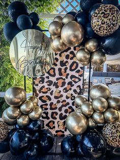 the balloon arch is decorated with black, gold and leopard print balloons that spell out happy birthday