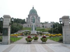 a large building with a statue in the middle and flowers around it on either side