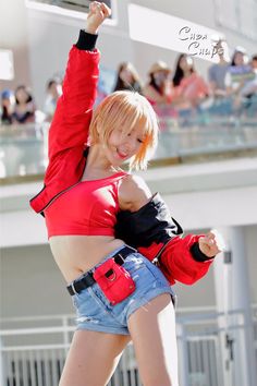 a woman in short shorts and a red top is dancing with her hands up to the side