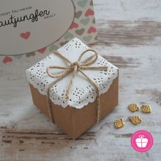 a small gift box tied with twine and surrounded by tiny gold heart decorations on a table