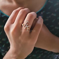 a woman wearing a diamond ring with the letter k on it